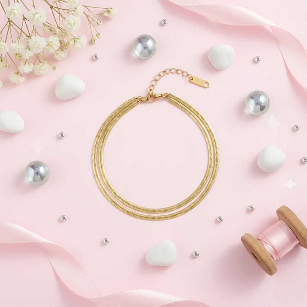 Gold bracelet on a wrist with a pink background