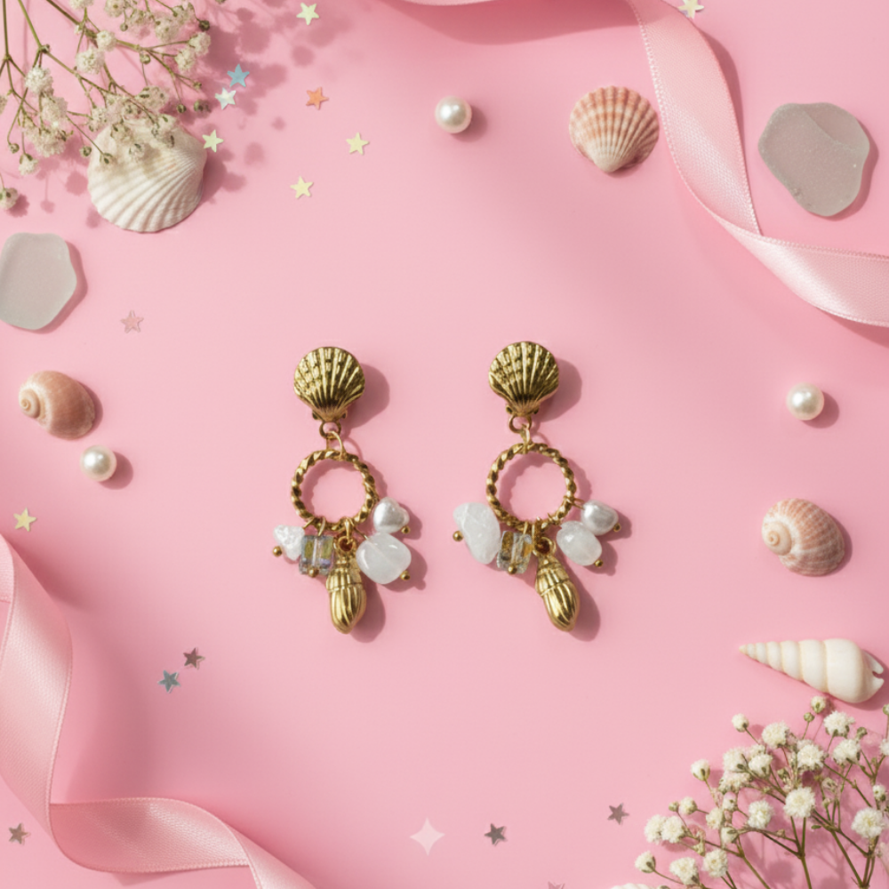 Gold earrings with shell and bead charms on a pink background