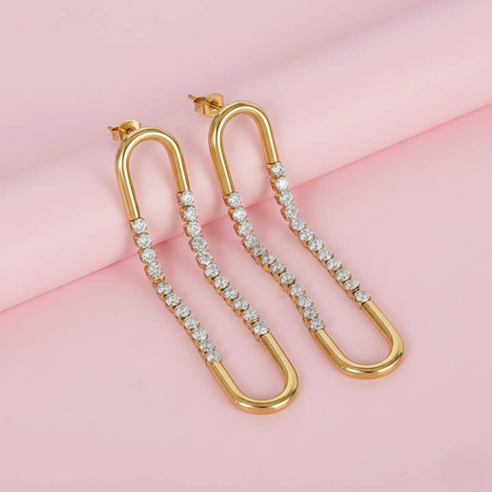 Gold hoop earrings with embedded diamonds on a pink background