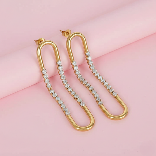 Gold hoop earrings with embedded diamonds on a pink background