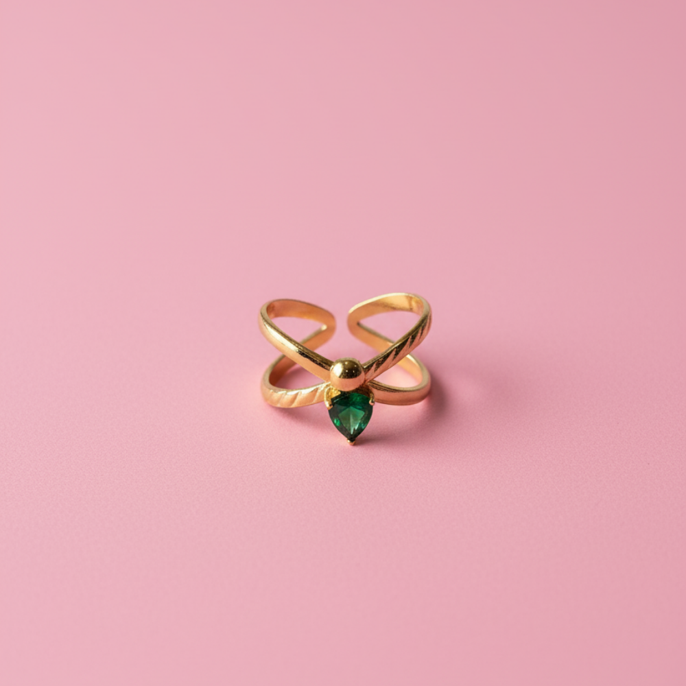 Gold ring with a green gemstone on a pink background