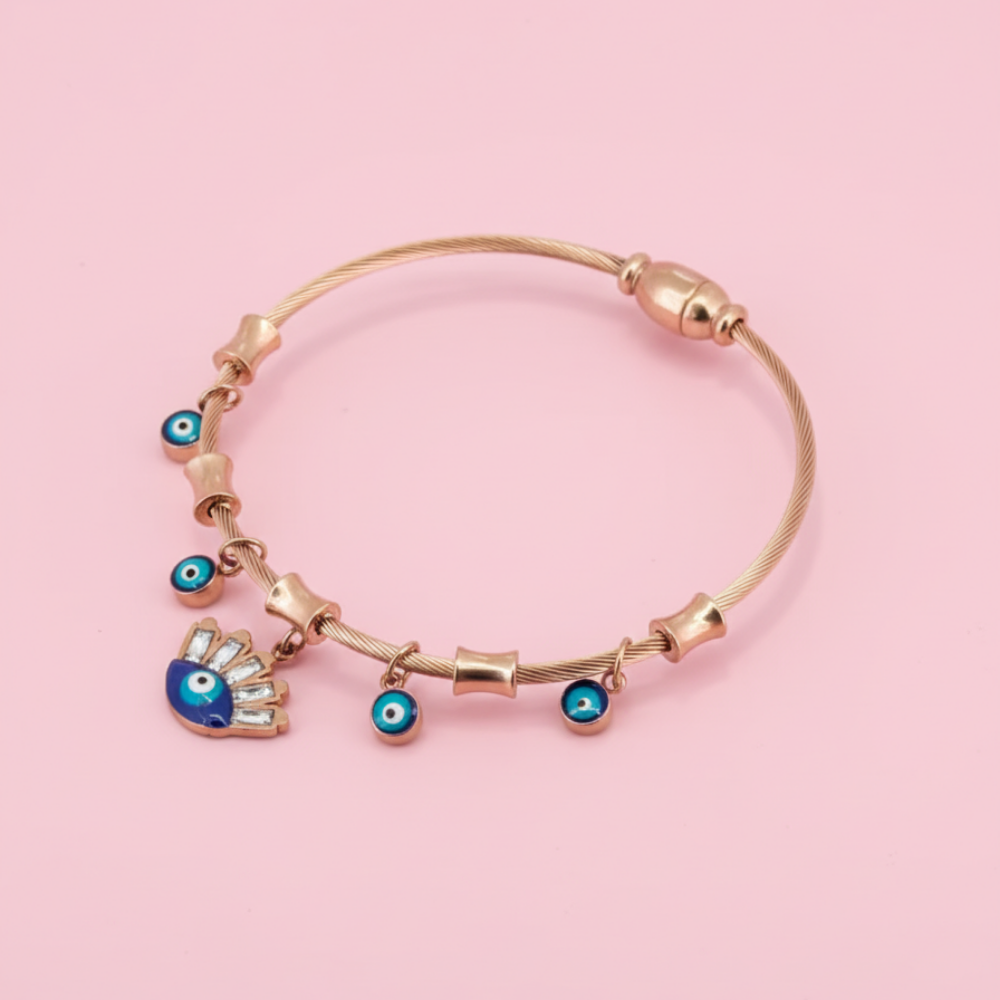 Rose gold bracelet with evil eye charms on a pink background