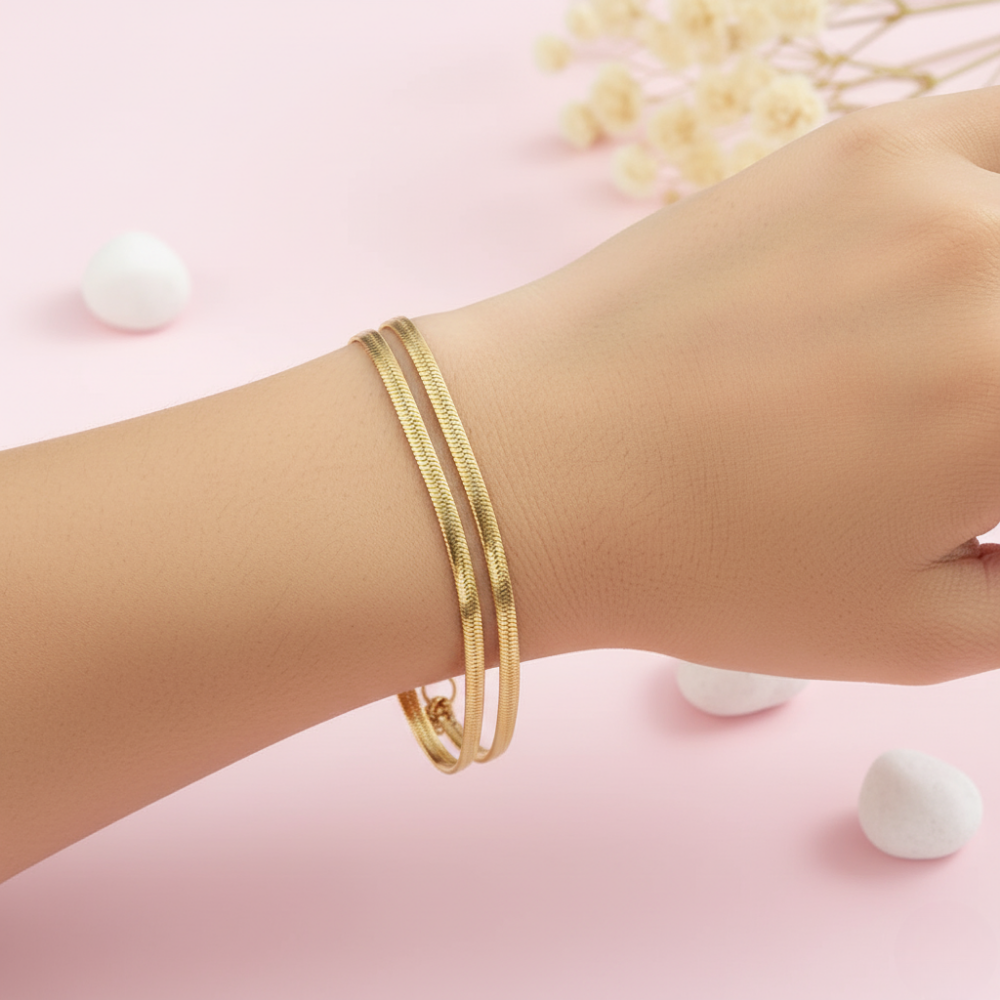 Gold bracelet on a wrist with a pink background