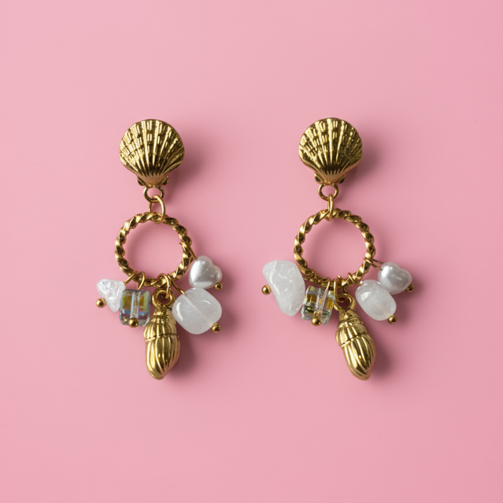 Gold earrings with shell and bead charms on a pink background