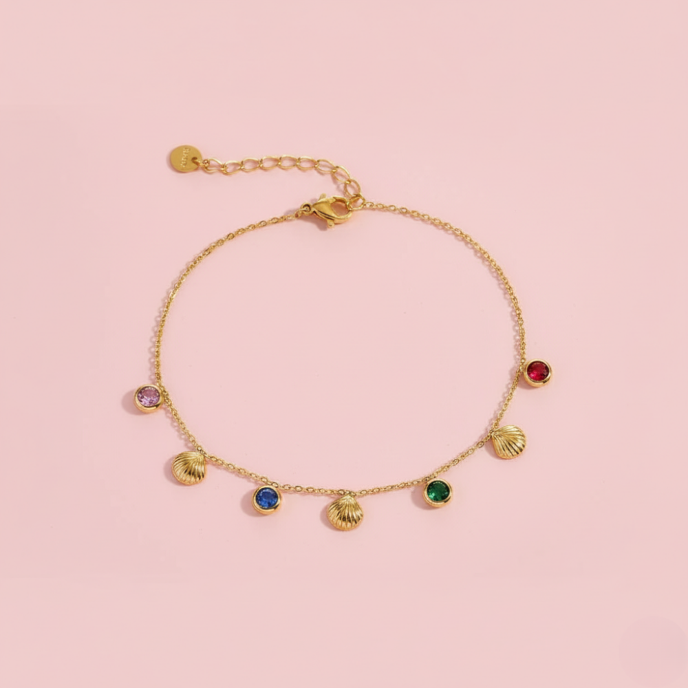Gold bracelet with colorful gemstones on a pink background