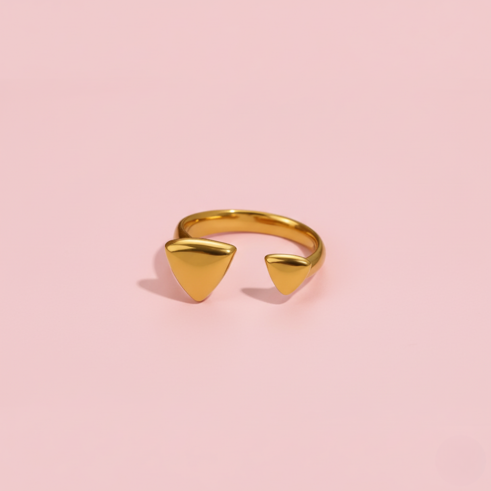 Gold open ring with triangular designs on a pink background